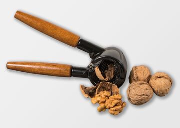 Ansicht auf den Nussknacker mit Holzgriff und schwarzem Werkzeug mit Walnüssen.