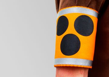 Ansicht eines Oberarms mit der gelben Armbinde, auf der drei schwarze Punkte sind.
