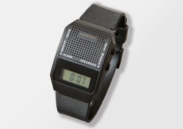 Ansicht auf die schwarze Uhr mit Display in einem transparenten Ständer.