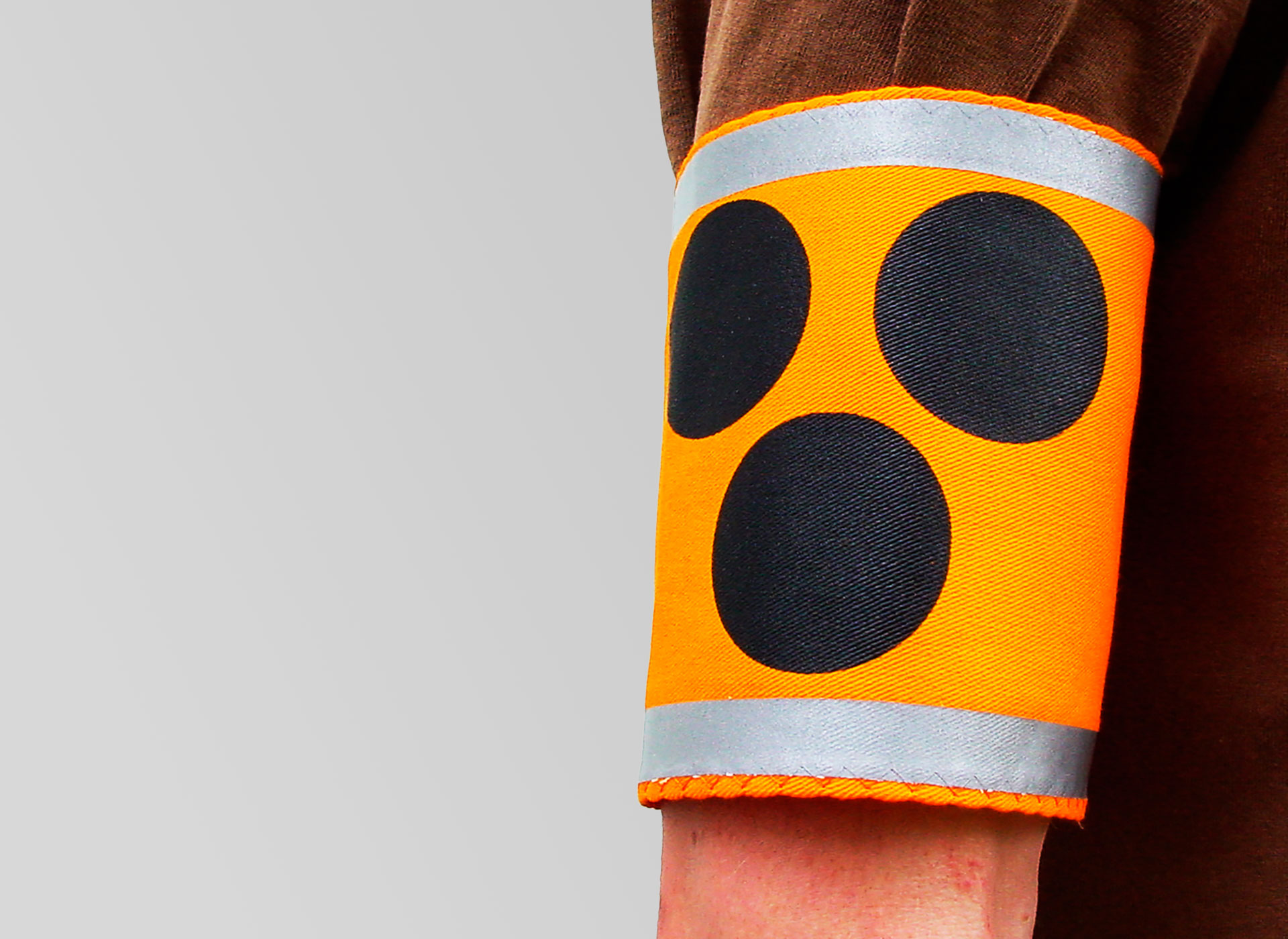 Ansicht eines Oberarms mit der gelben Armbinde, auf der drei schwarze Punkte sind.