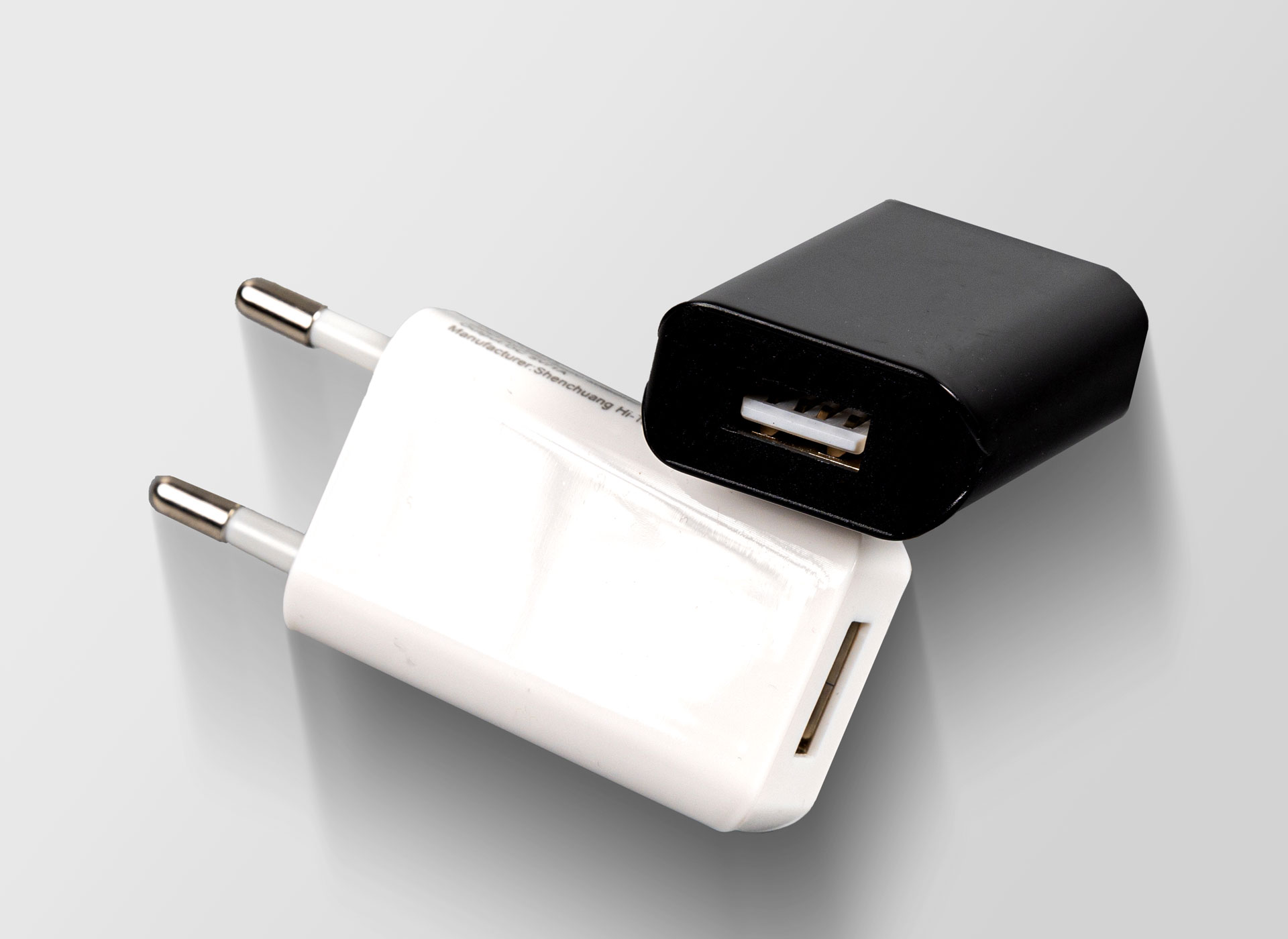 Ansicht auf das weiße Netzteil. Ein Schwarzes liegt schräg dahinter.